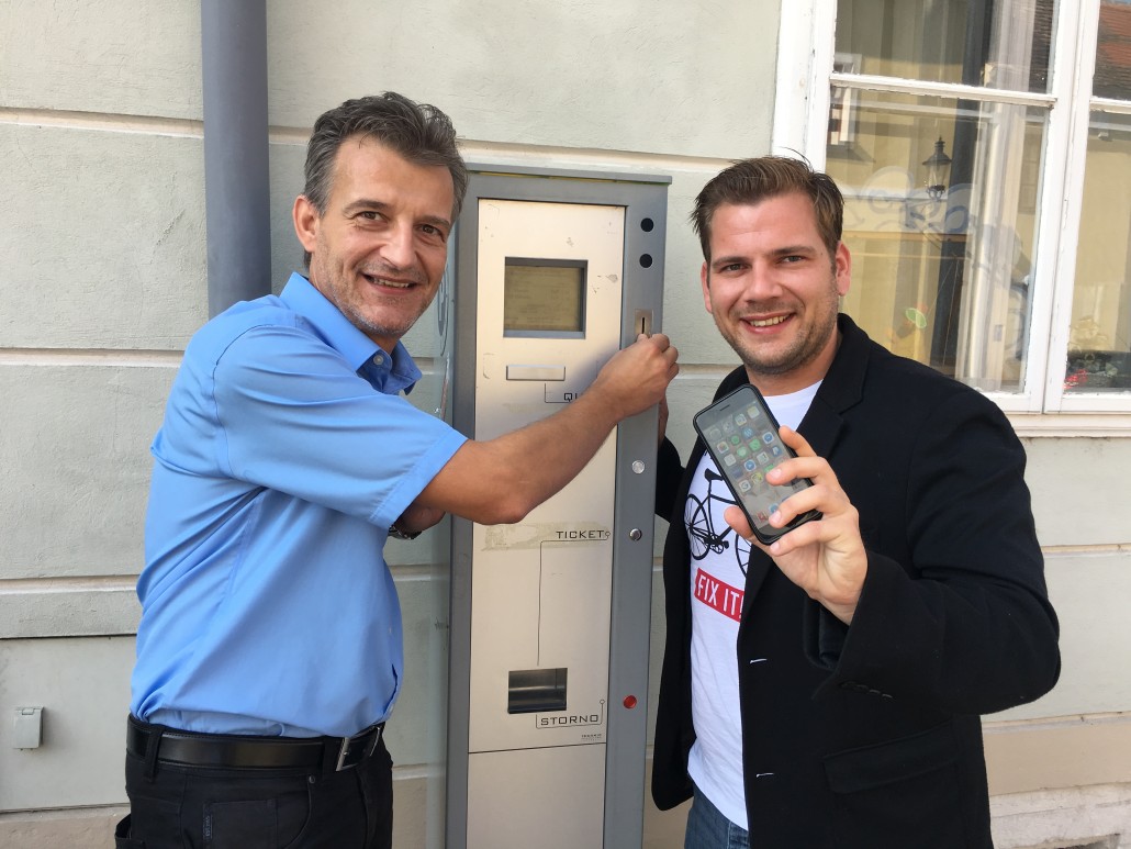 Verkehrsstadtrat Peter Zemann und STR Alexander Petznek fordern neben dem vorhandenen Parkautomaten, mit einer Handy-App die Parkgebühren begleichen zu können.